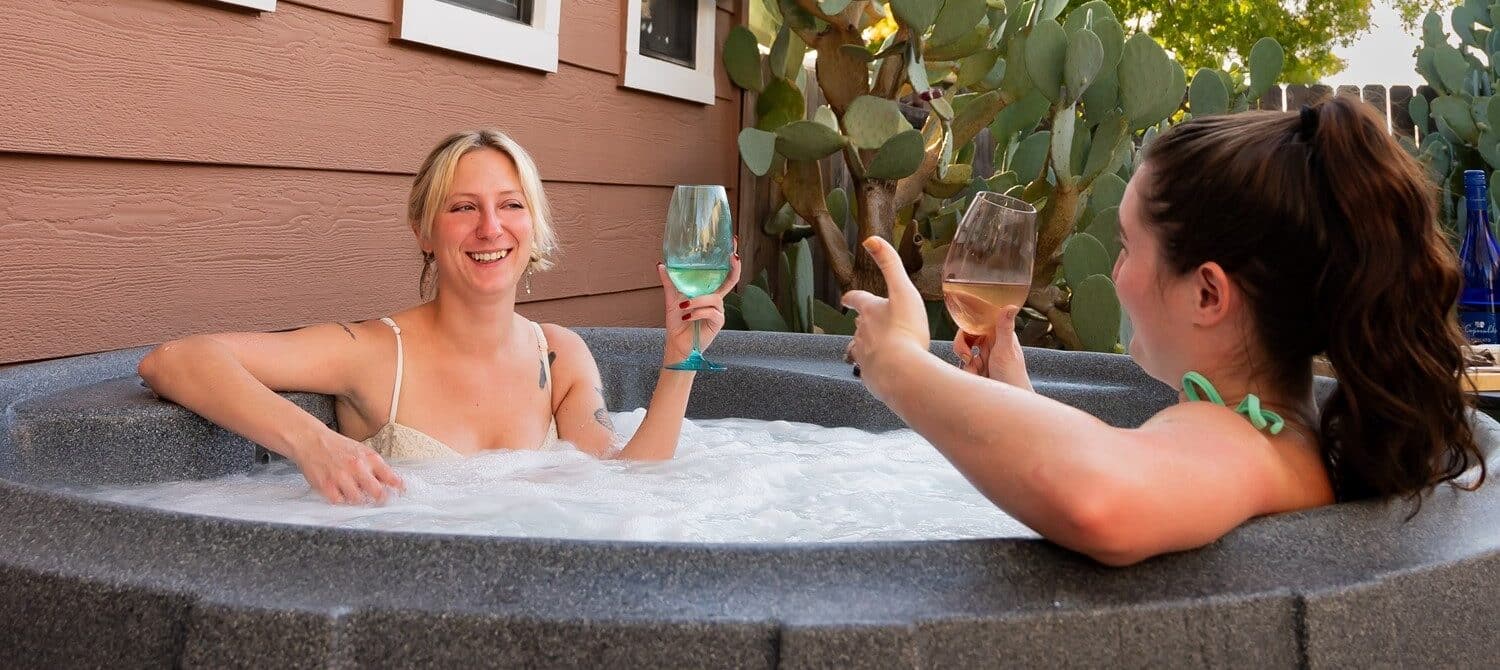 Two women in a hot tub enjoying a glass of wine