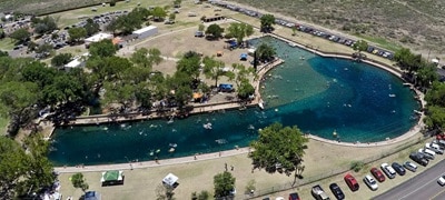 an aerial shot of a large pool with people swimming and playing.