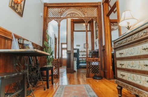 a front hallway with wood floors, antique tables and wood spindlework