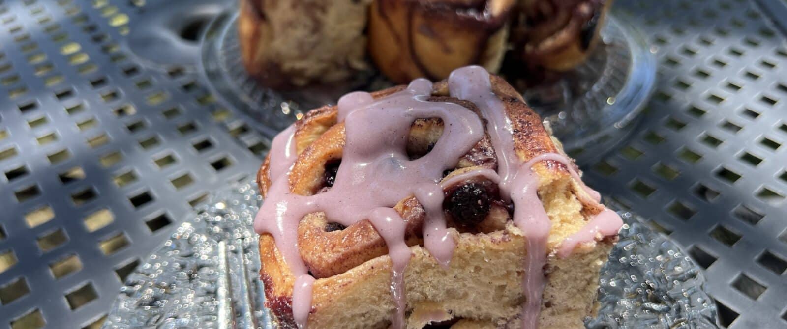 blueberry cinnamon rolls shown on a plate that's on an outdoor table.