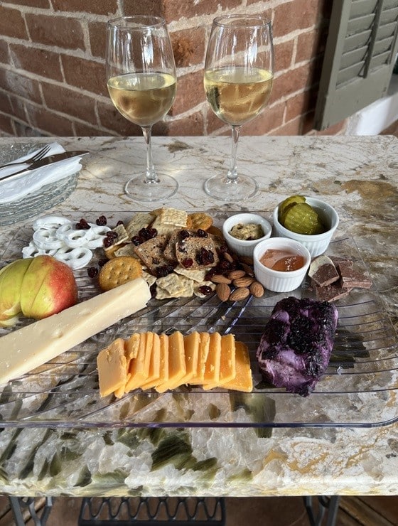 Charcuterie board of crackers, chocolate, nuts and cheeses with two glasses of wine