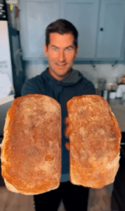 A man holding two loaves of golden bread