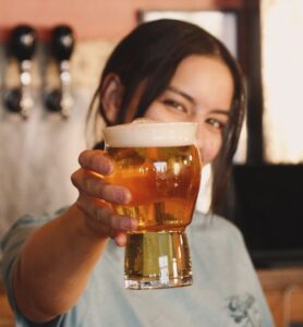 a woman holding up a glass of beer