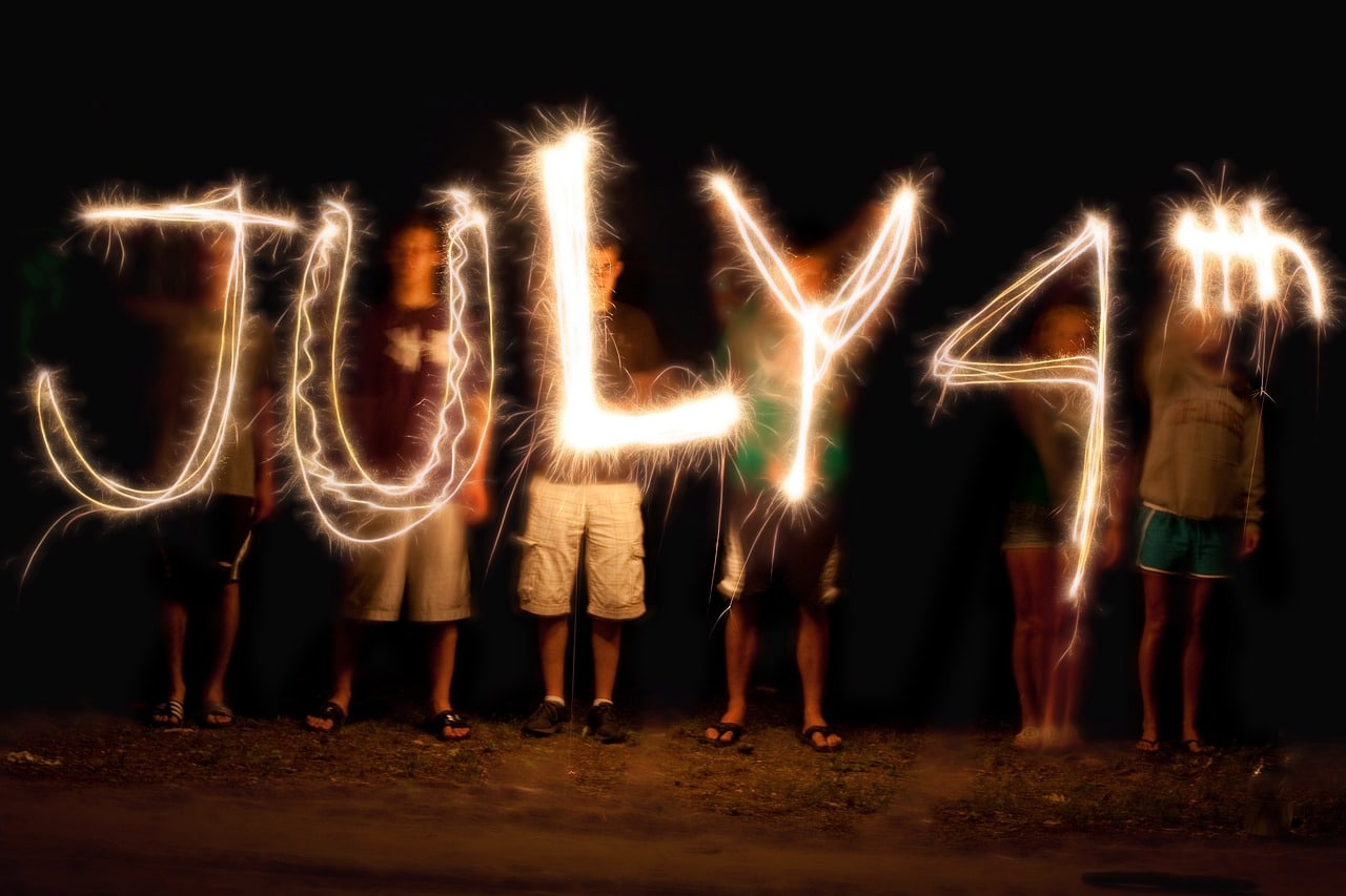 people standing with July 4th written in lights in front of them